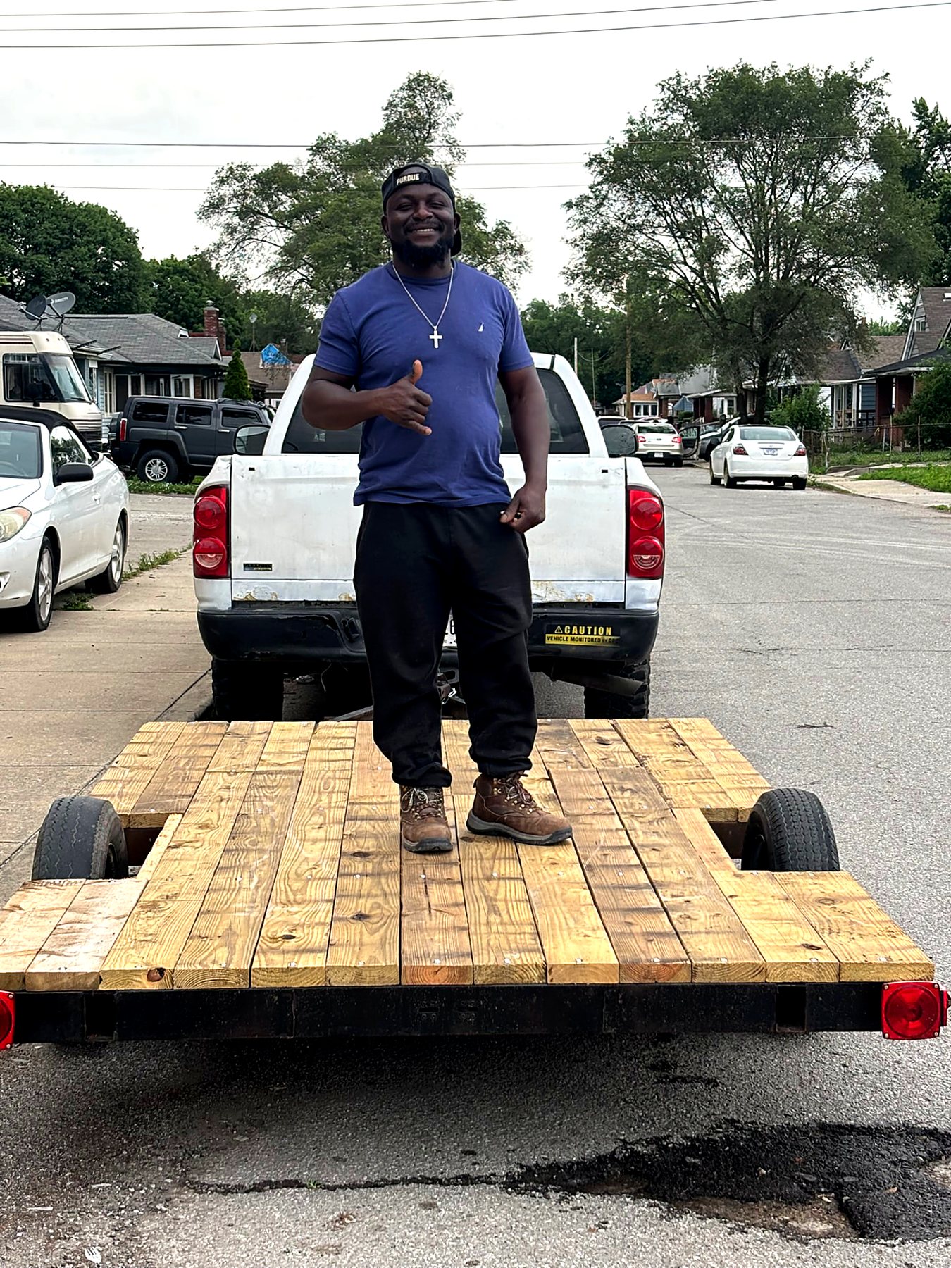Owner standing on the flatbed trailer used for large junk removal loads