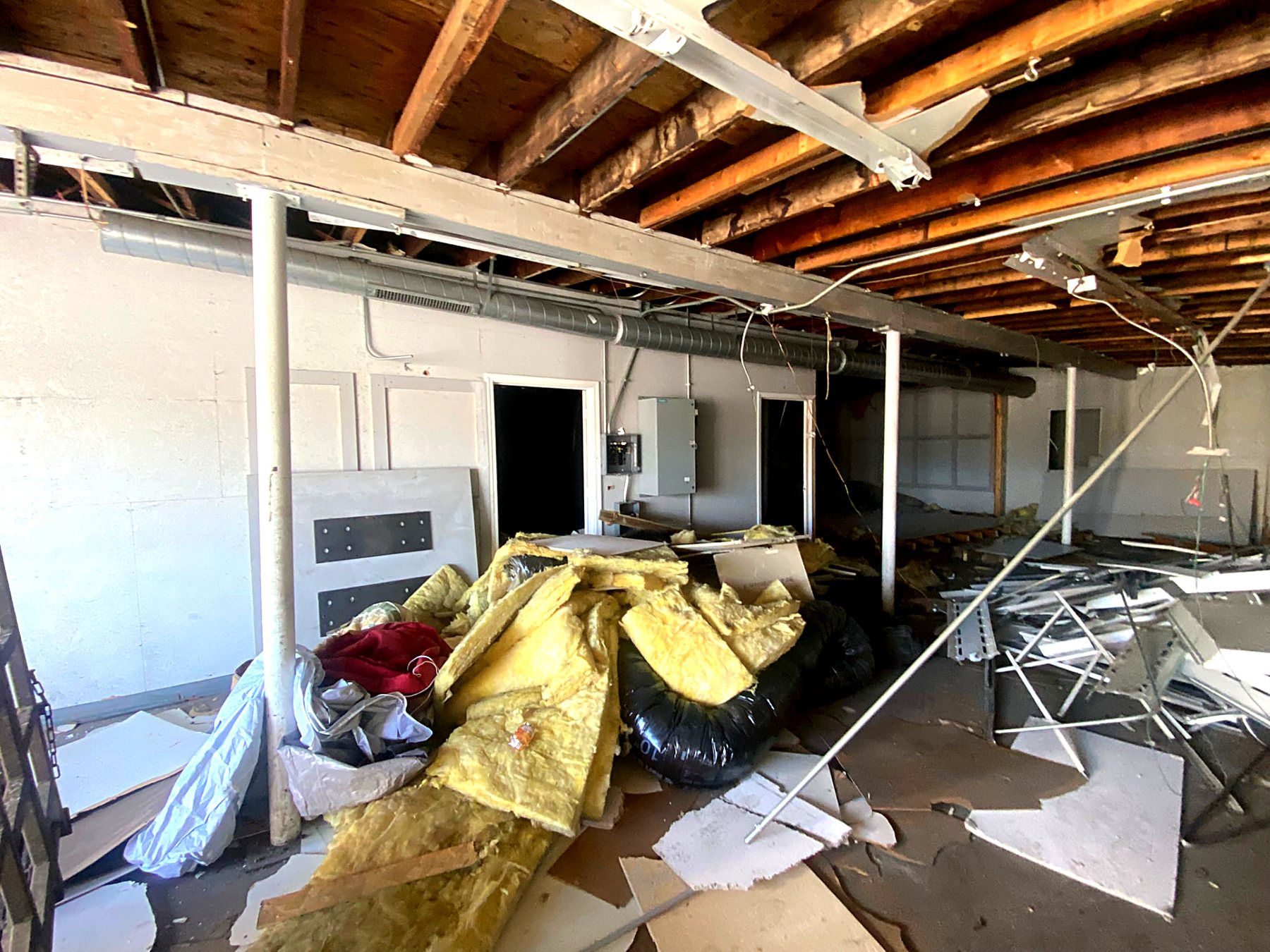 Piles of insulation, drywall, and construction debris stacked in a lower level