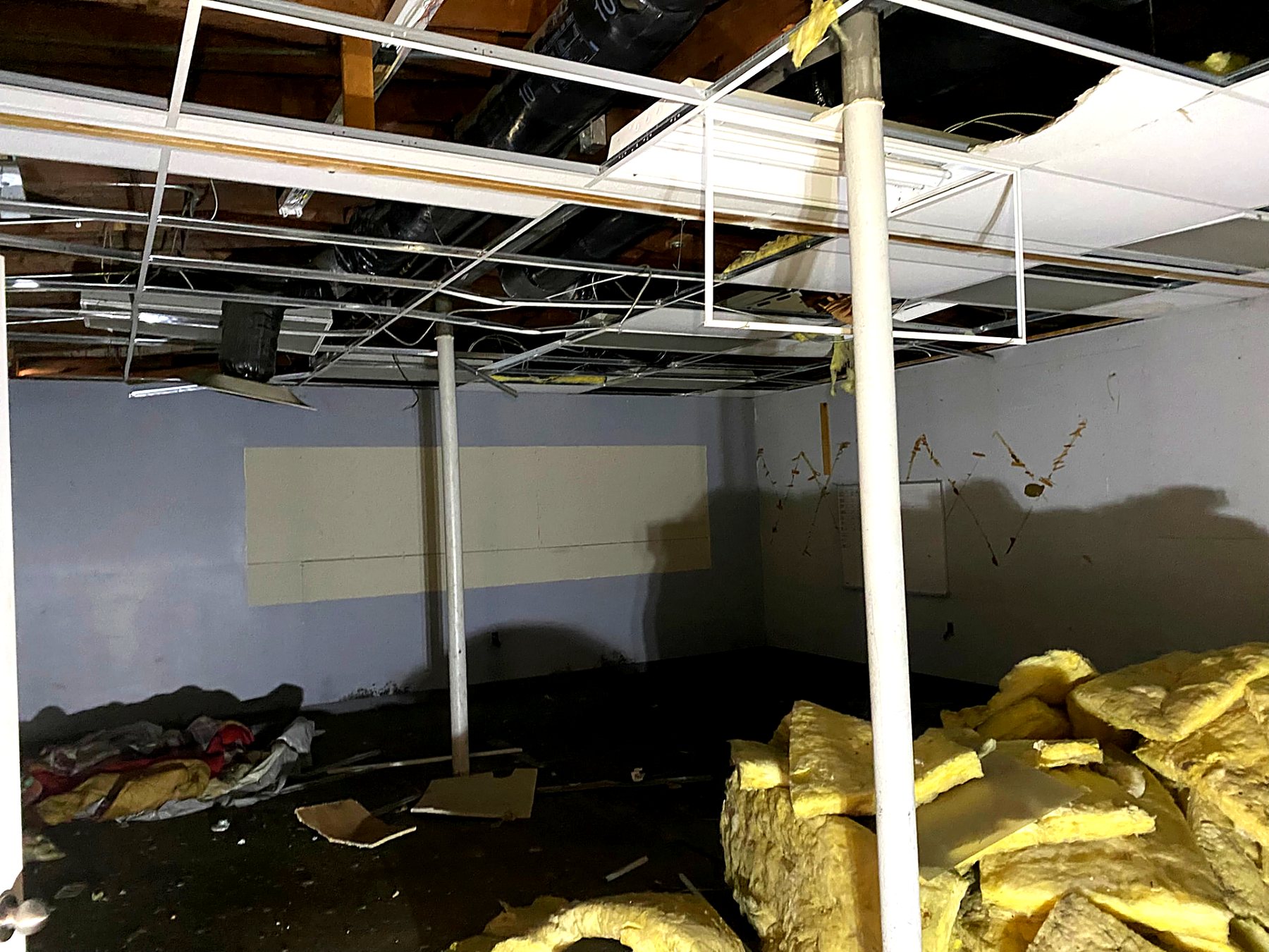 Basement full of torn-out insulation, ceiling tiles, and debris before cleanout